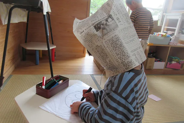 大切にしていること新聞紙をかぶり絵を描く子供