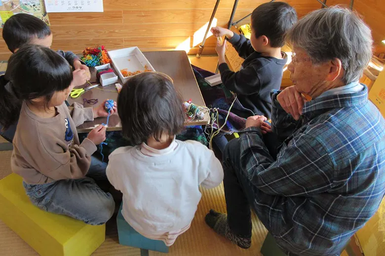 大切にしていること先生と机を囲み工作する子どもたち