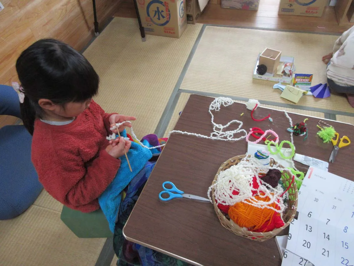 編み棒で編み物をする子ども